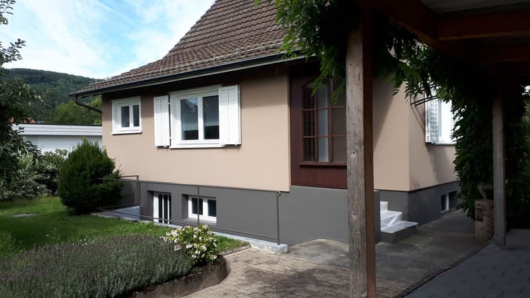 Wohnhaus mit warm beiger Fassade und grauem Sockel