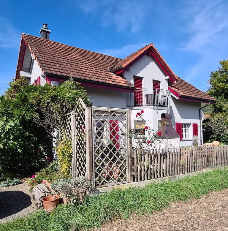 Wohnhaus mit weisser Fassade und kräftig pinken Fensterläden