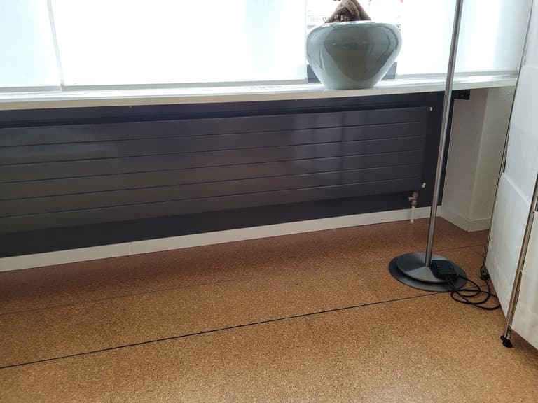Dunkler Heizkörper vor Nische, darunter Korkboden