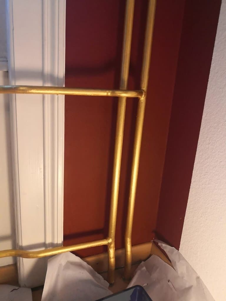 Gold gefasste Heizungsrohre vor dunkelroter Wand