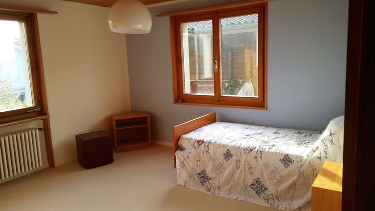 Schlafzimmer mit hellblauer Wand und Holzfenstern