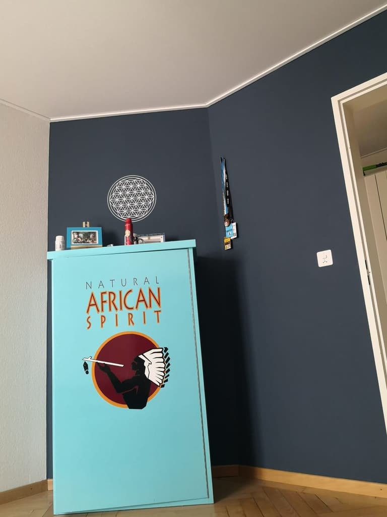 Raumecke mit tiefblauer Wand und türkisfarbenem Möbel
