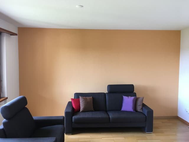 Wohnzimmer mit warm oranger Wandfläche